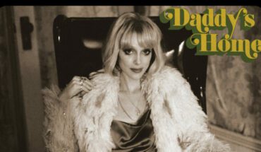 St. Vincent Daddy's Home album cover. Annie Clark is sitting on a chair in a silk dress and fur coat in a sepia tone photograph.